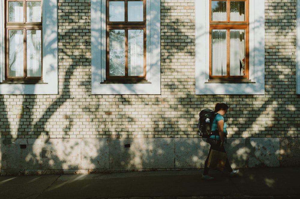 woman in black jacket and black pants standing in front of white brick wall