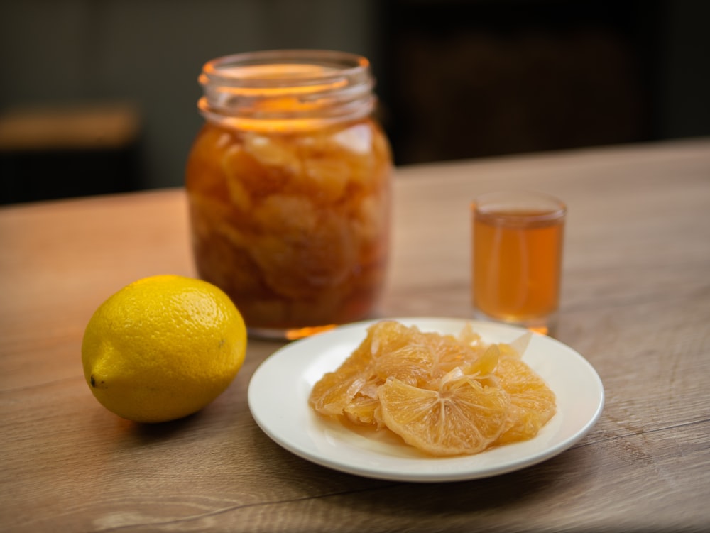 un plato blanco cubierto con naranjas en rodajas junto a un frasco de miel