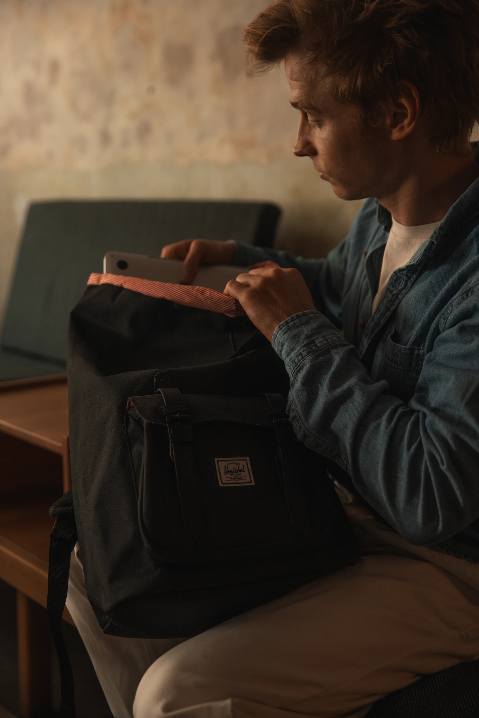 Man packing a black Herschel backpack