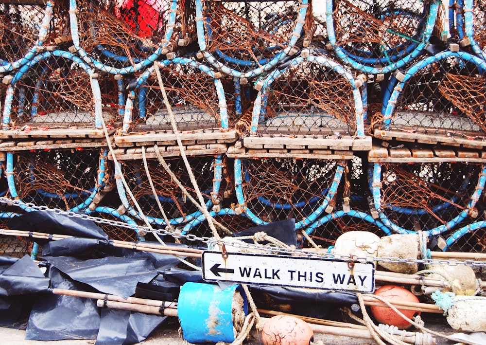 uma pilha de redes de pesca com uma placa que diz andar desta maneira
