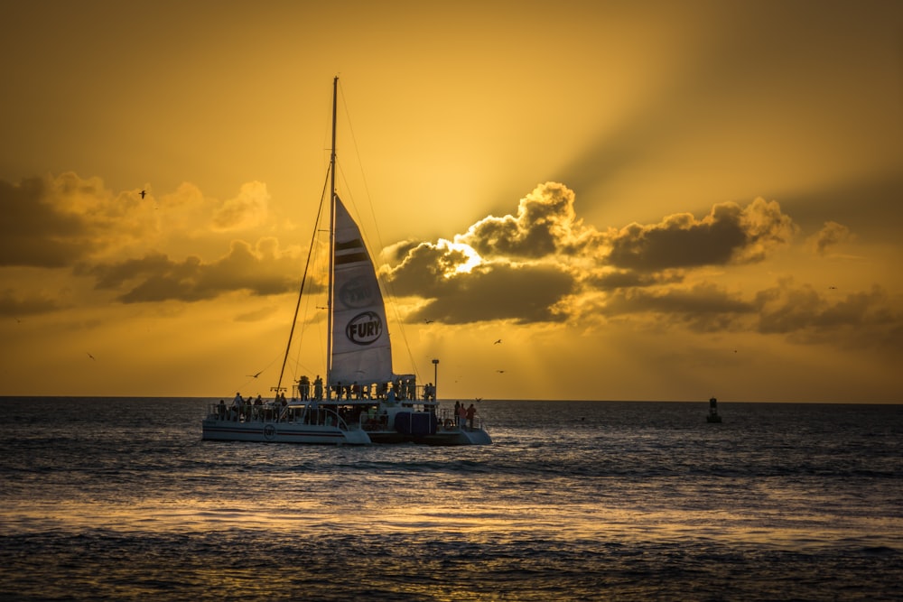 white sail boat on sea during sunset