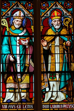 a stained glass window with a man holding a cross