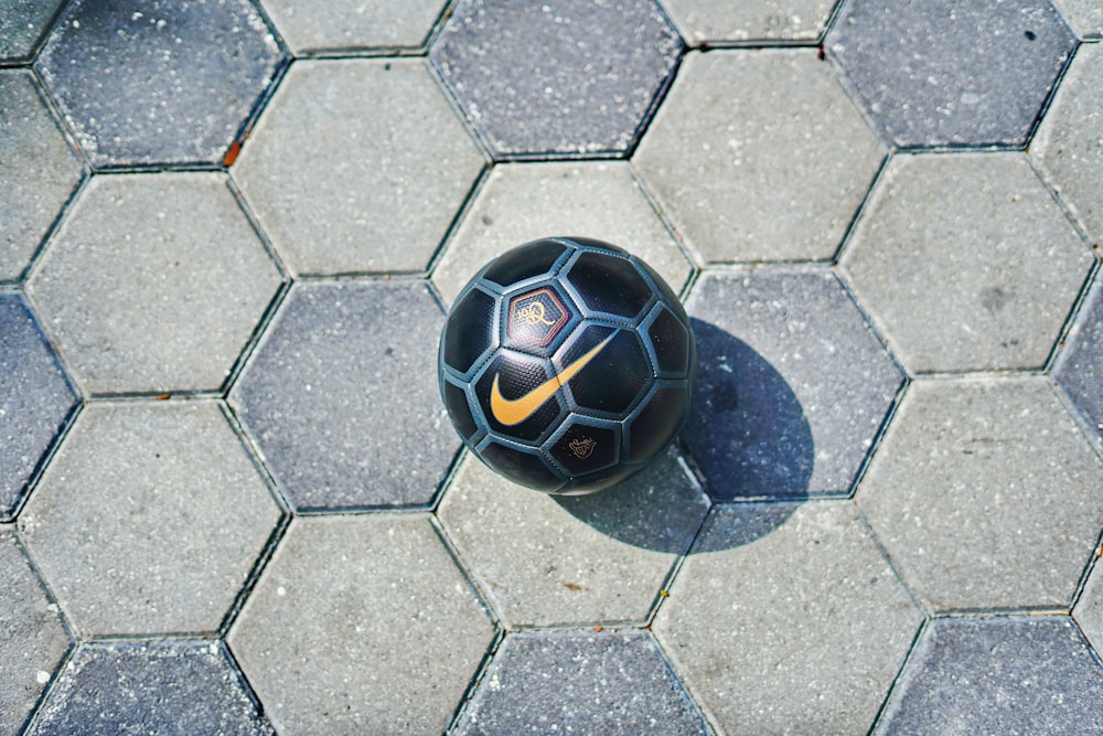 a black soccer ball sitting on top of a stone floor