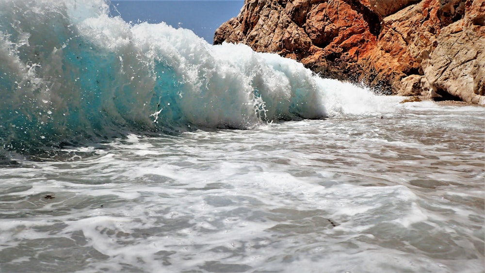 a large wave crashing into a rocky shore