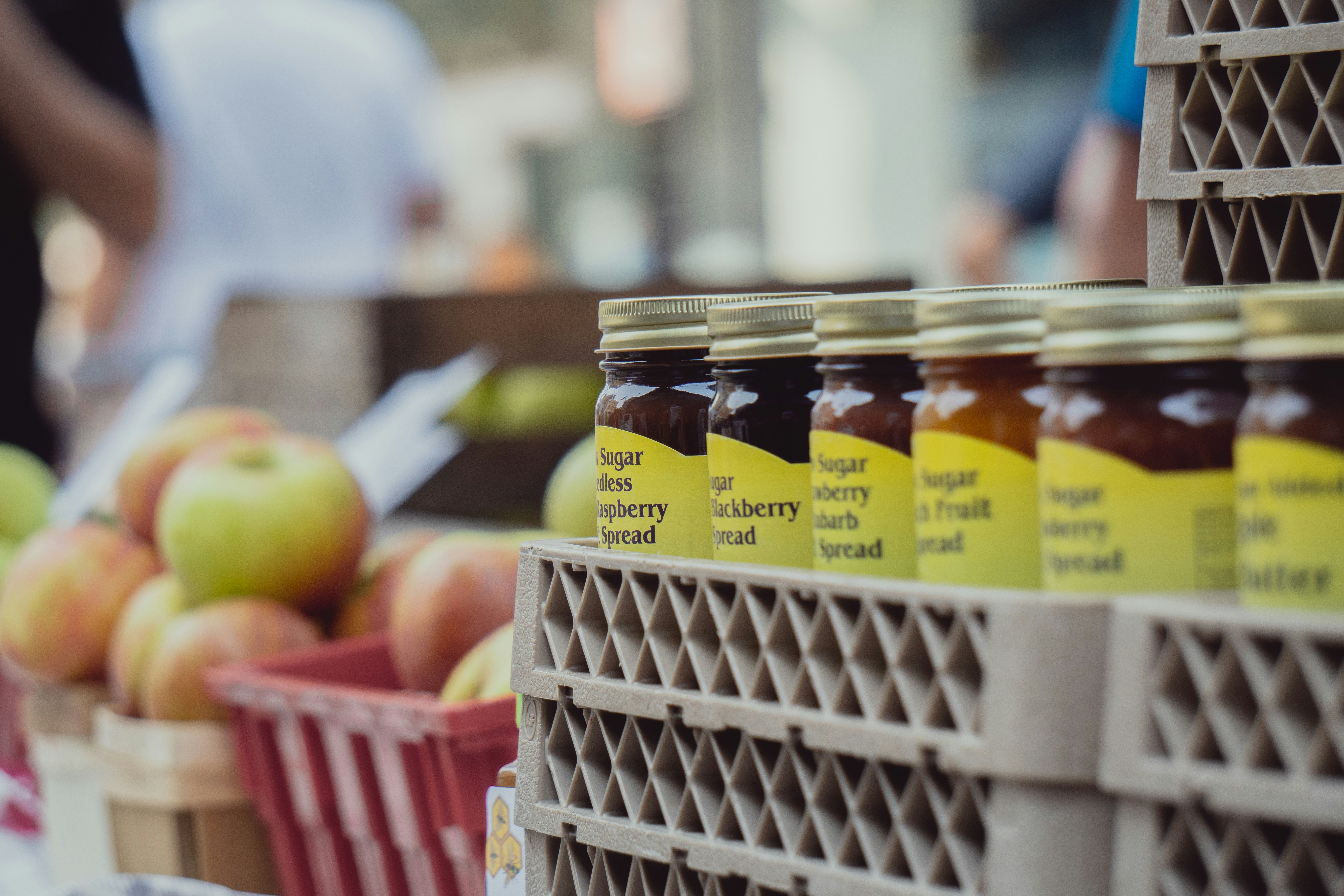 Gläser mit Honig stehen auf einem Tisch vor Äpfeln
