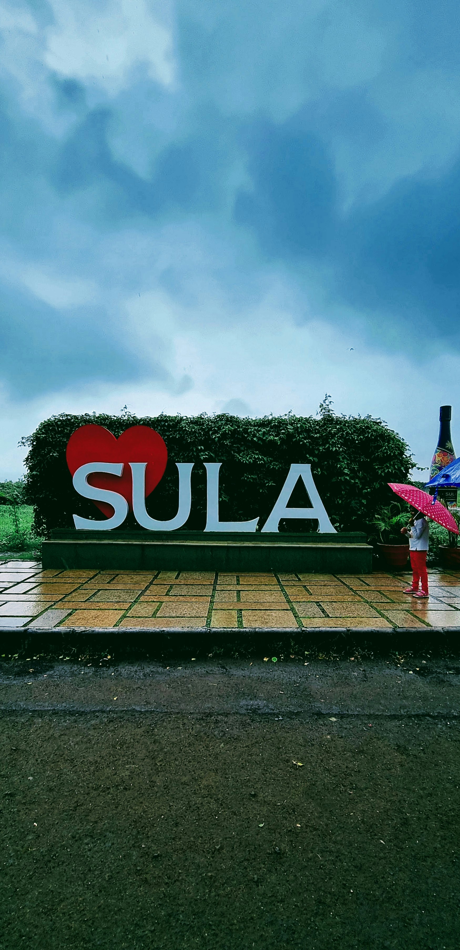 A girl with umbrella standing near a big logo