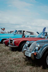 red and black vintage car on green grass field during daytime
