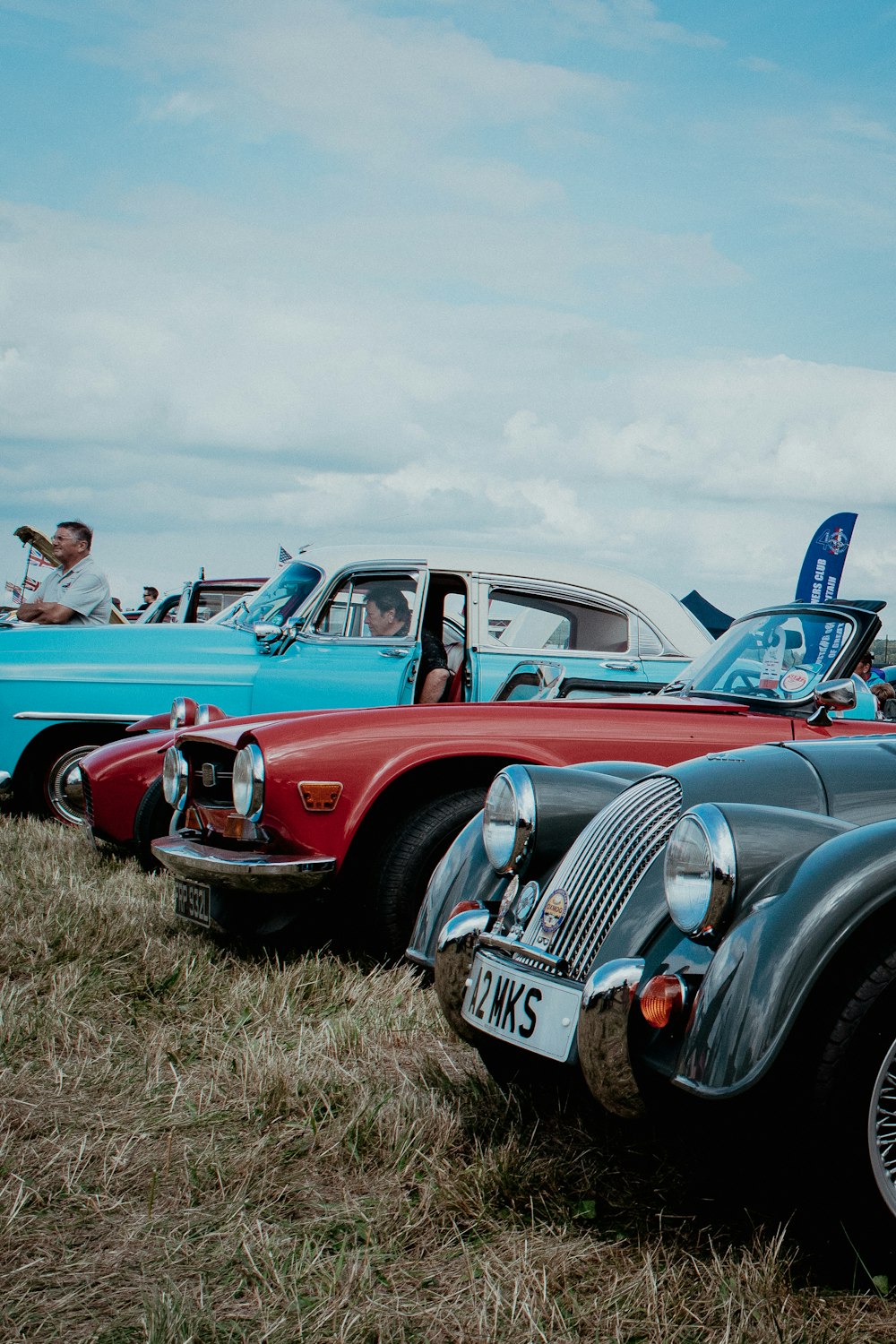 red and black vintage car on green grass field during daytime