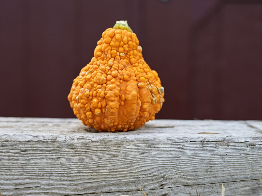 Una pequeña calabaza sentada encima de una mesa de madera