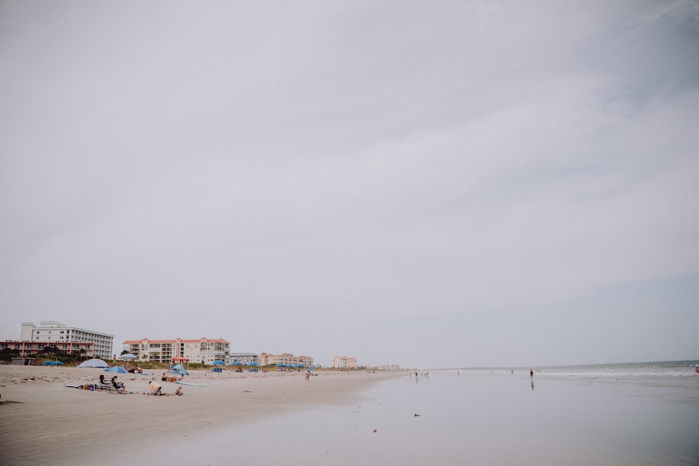 a sandy beach with people on it and buildings in the background