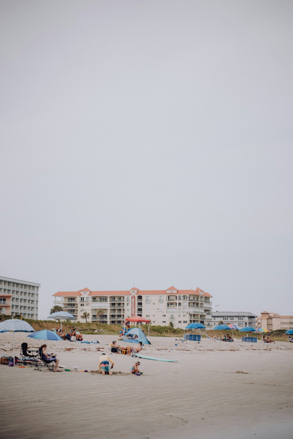 a group of people sitting on top of a sandy beach