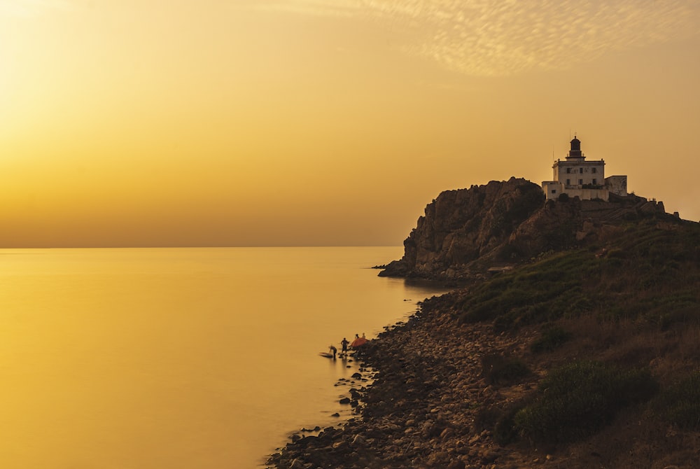 a light house sitting on top of a hill next to a body of water