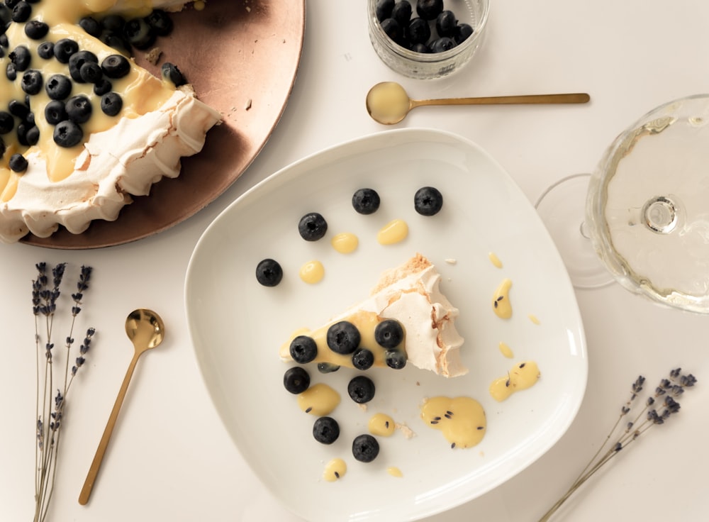 une assiette blanche garnie d’un morceau de gâteau à côté d’un verre de vin