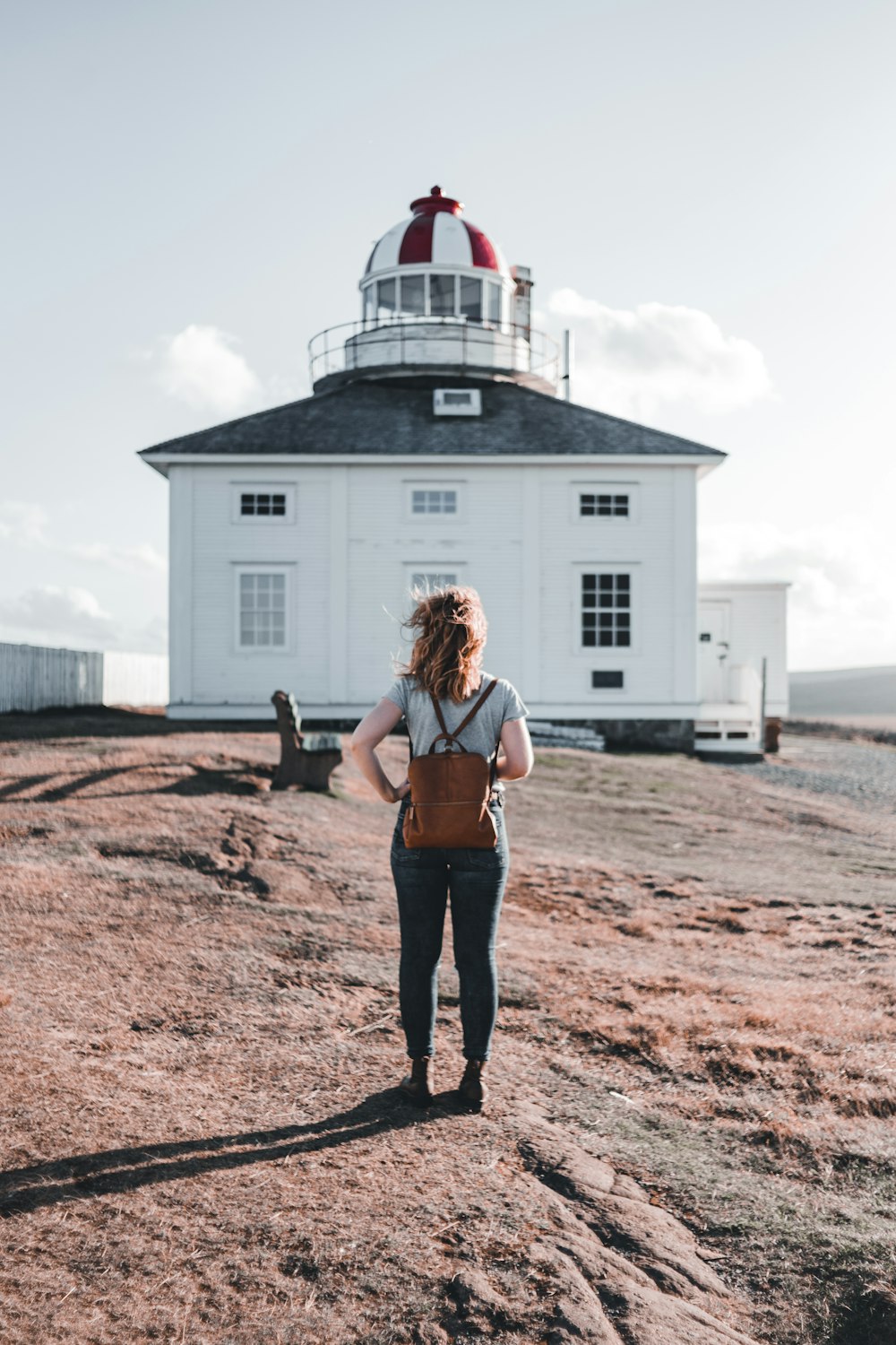 woman in black shorts standing on brown sand near white house during daytime