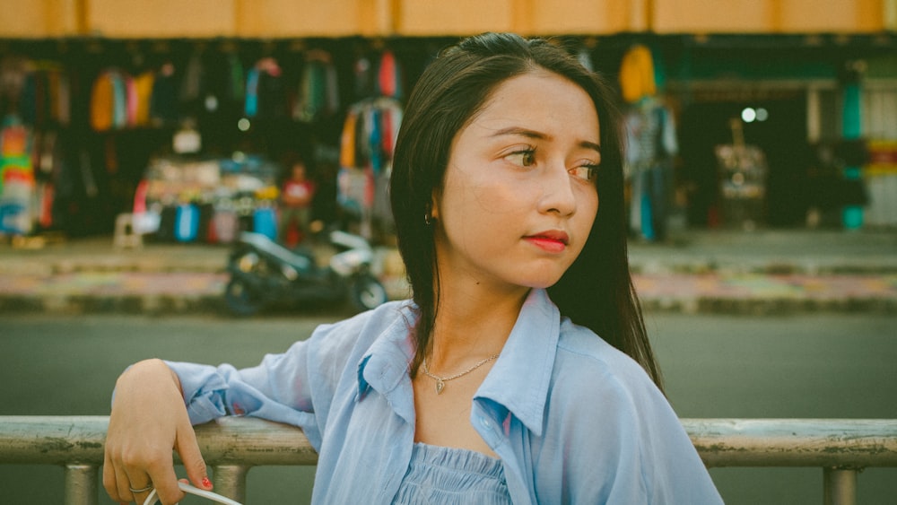 a woman leaning on a rail in front of a store