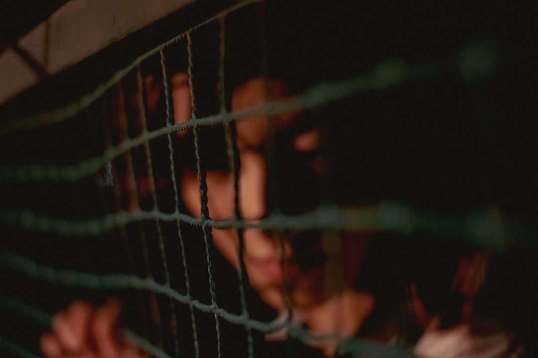 person in black shirt standing behind black metal fence