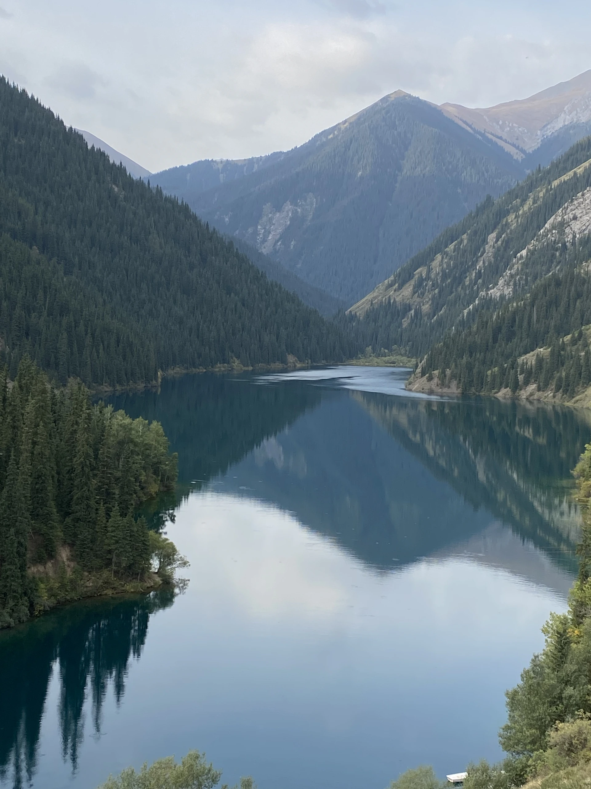 A delicate pencil sketch of a serene mountain landscape with a calm lake reflecting the sky.