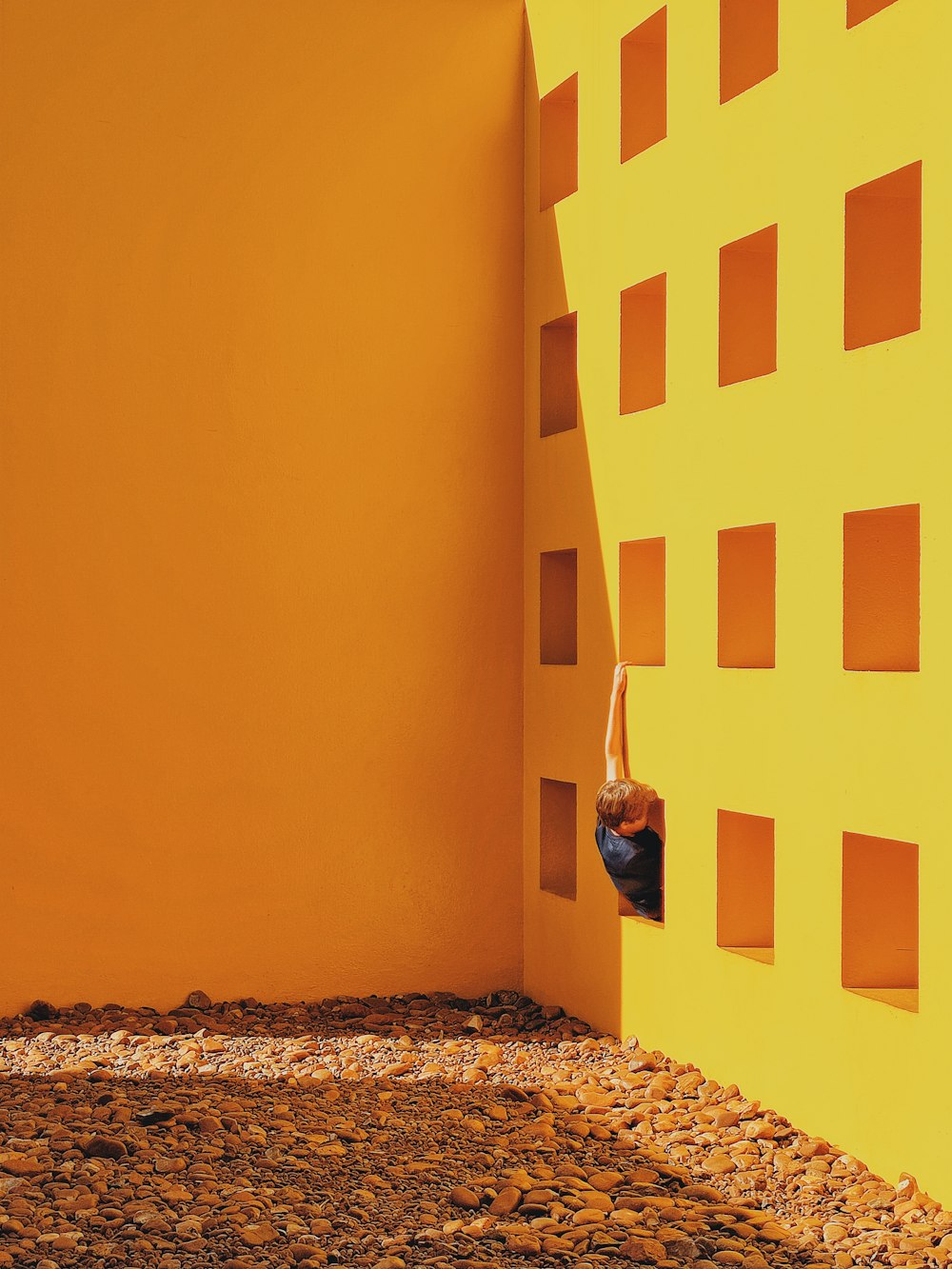 man in black jacket standing beside yellow painted wall