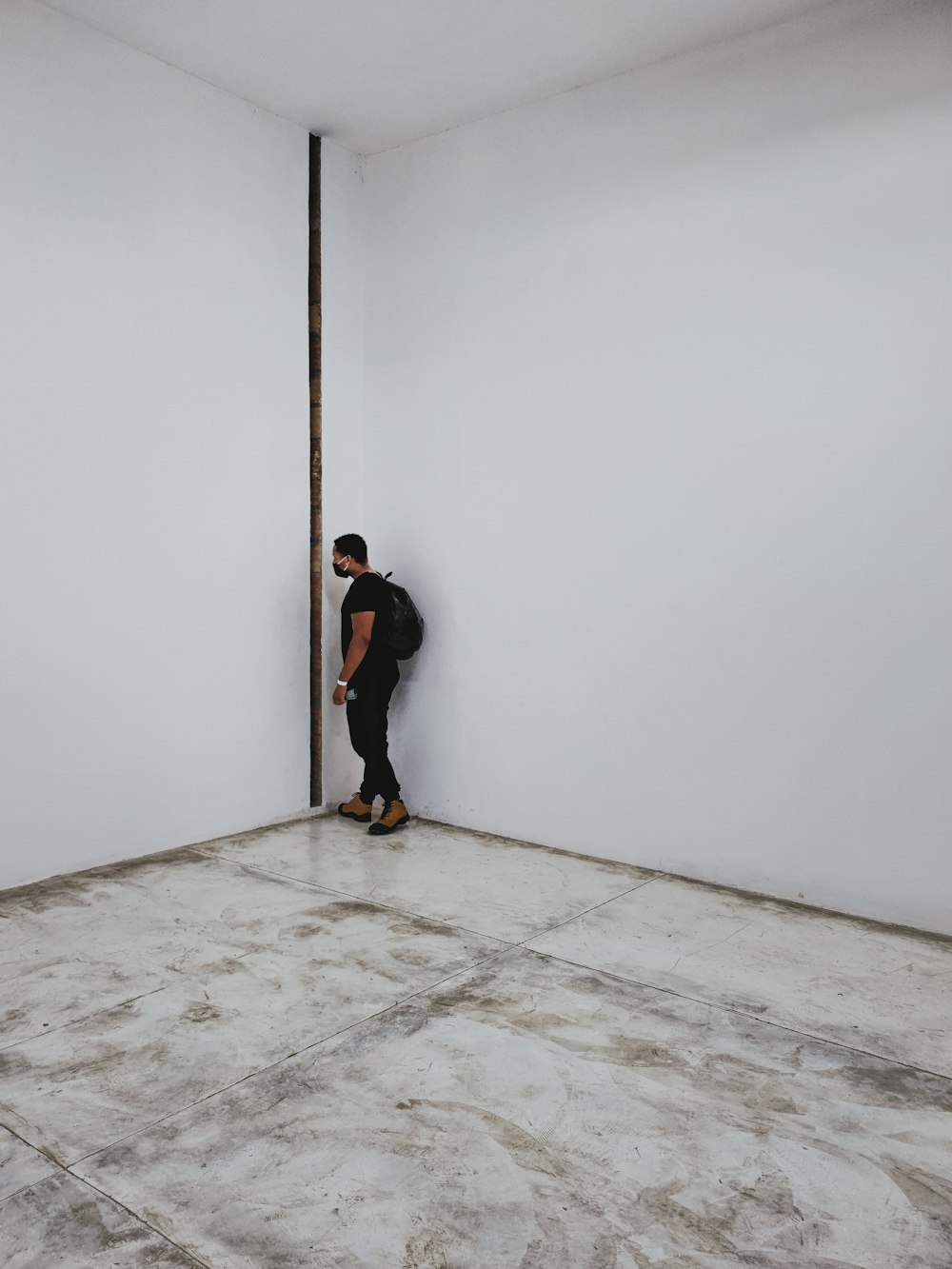 man in black jacket and black pants walking on white floor tiles