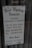 A sign for 'The West Wyalong Advocate' newspaper, detailing publication days as Tuesdays and Fridays. The sign includes the street address, telephone and fax numbers, and office hours from Monday to Friday, 8 am to 5 pm. The background consists of a reflective glass surface with metal rivets at the top corners.