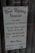 A sign for 'The West Wyalong Advocate' newspaper, detailing publication days as Tuesdays and Fridays. The sign includes the street address, telephone and fax numbers, and office hours from Monday to Friday, 8 am to 5 pm. The background consists of a reflective glass surface with metal rivets at the top corners.