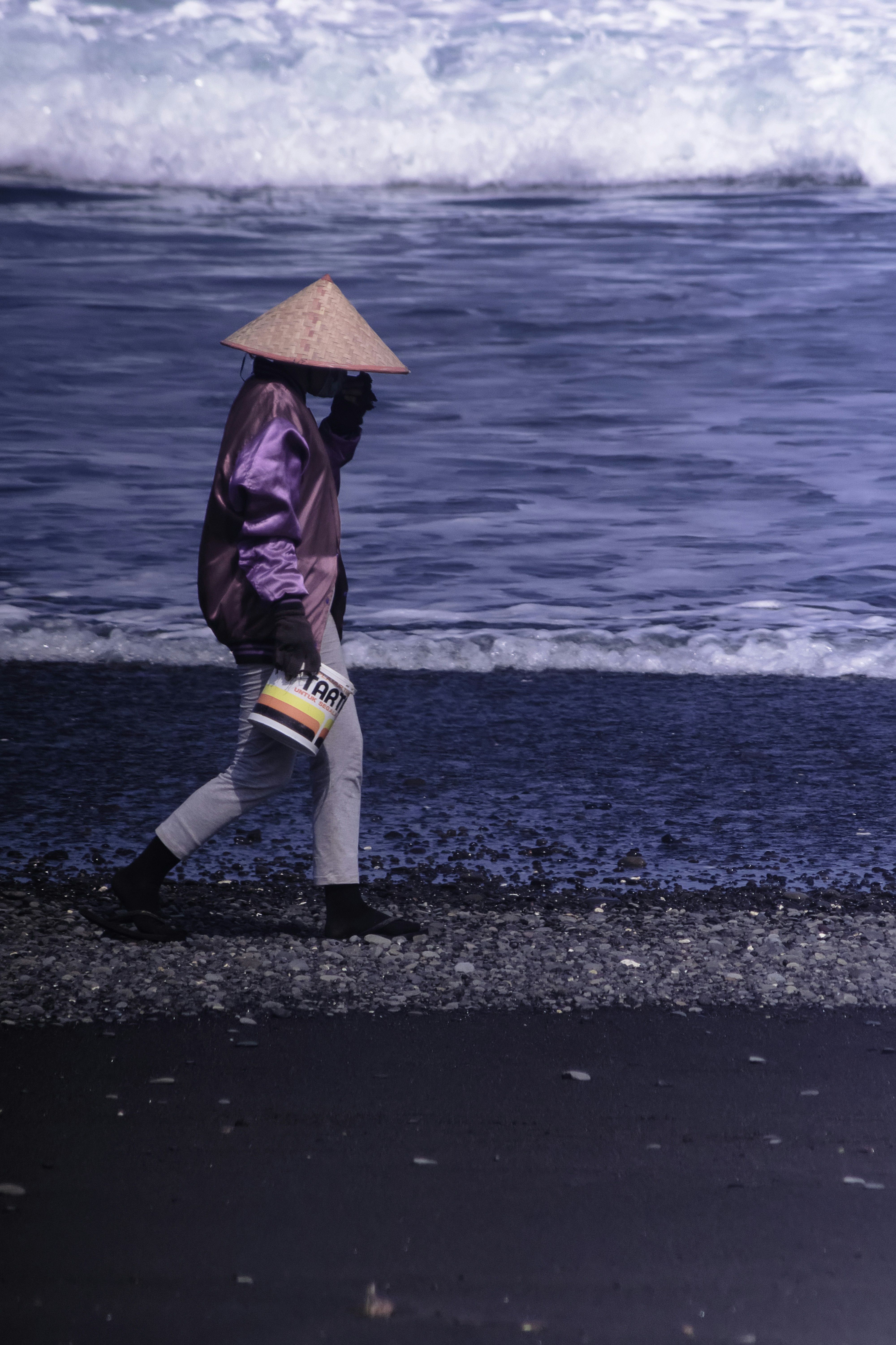 woman in brown leather jacket and white pants wearing red hat standing on beach during daytime