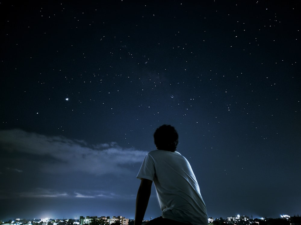 man in white t-shirt standing on field during night time