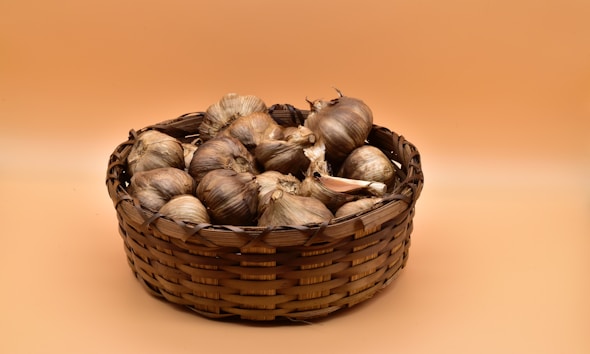 brown and white garlic on brown woven basket