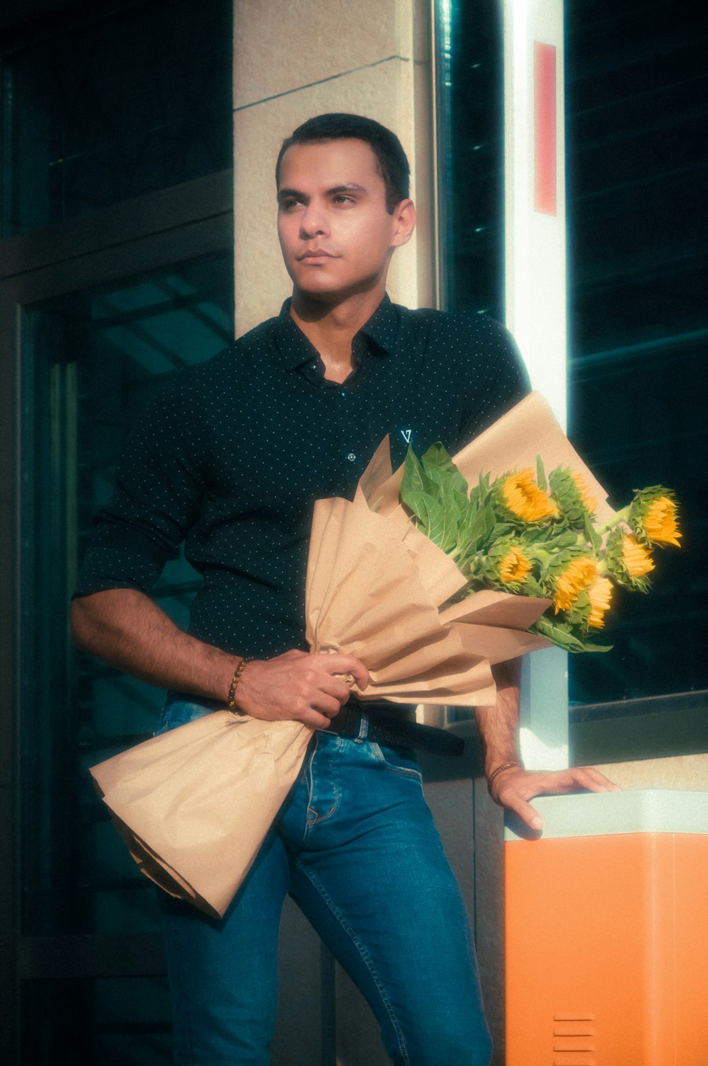 man in brown dress shirt holding bouquet of flowers
