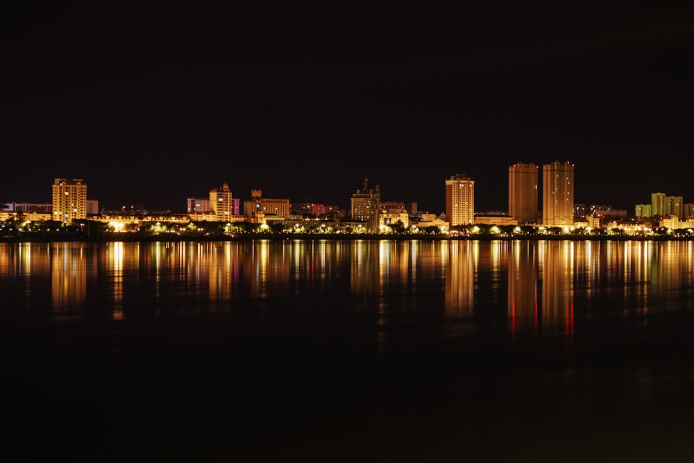 a city is lit up at night by the water