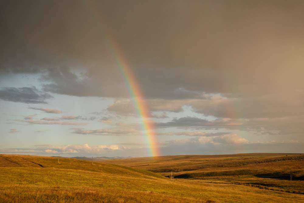 a rainbow in the sky over a grassy field