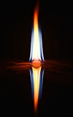 a flame is reflected in the water on a black background