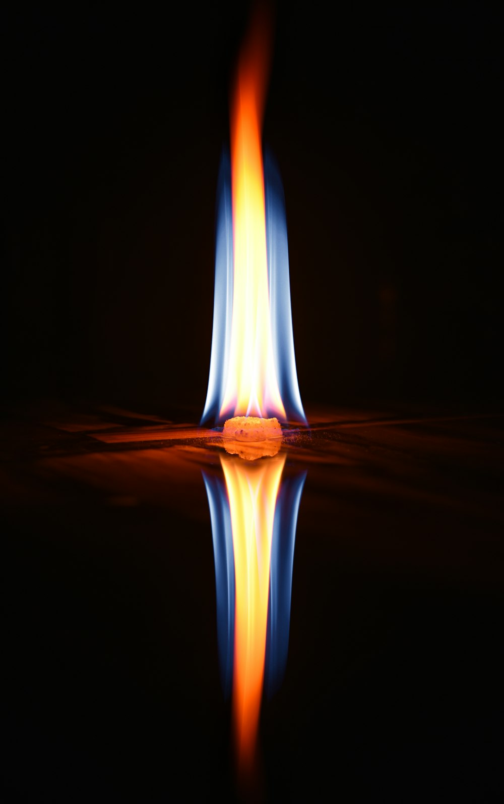 a flame is reflected in the water on a black background