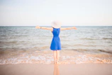 a woman in a blue dress standing on a beach