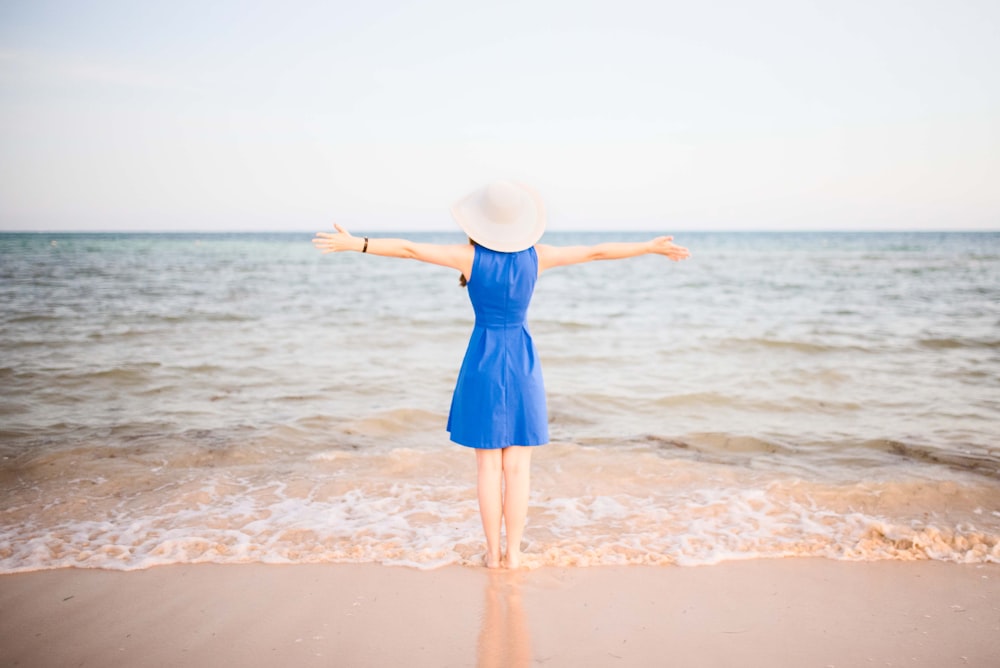 a woman in a blue dress standing on a beach