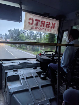 A professional bus driver behind the wheel of a modern coach on a scenic European highway.