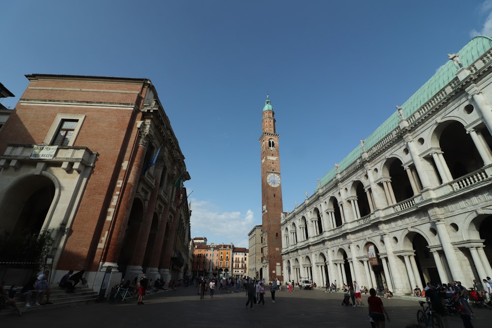 Persone che camminano sulla strada vicino all'edificio in cemento marrone durante il giorno