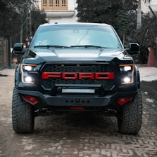 the front of a black truck parked on a cobblestone street