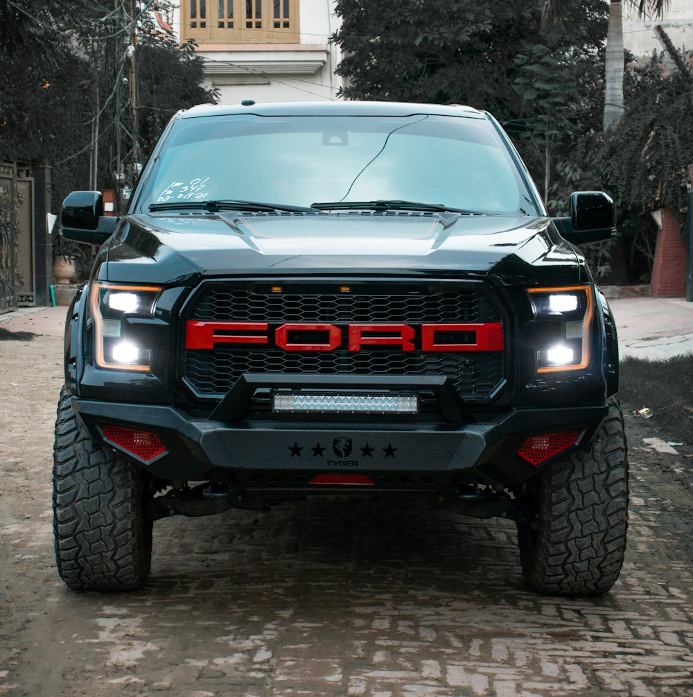 the front of a black truck parked on a cobblestone street