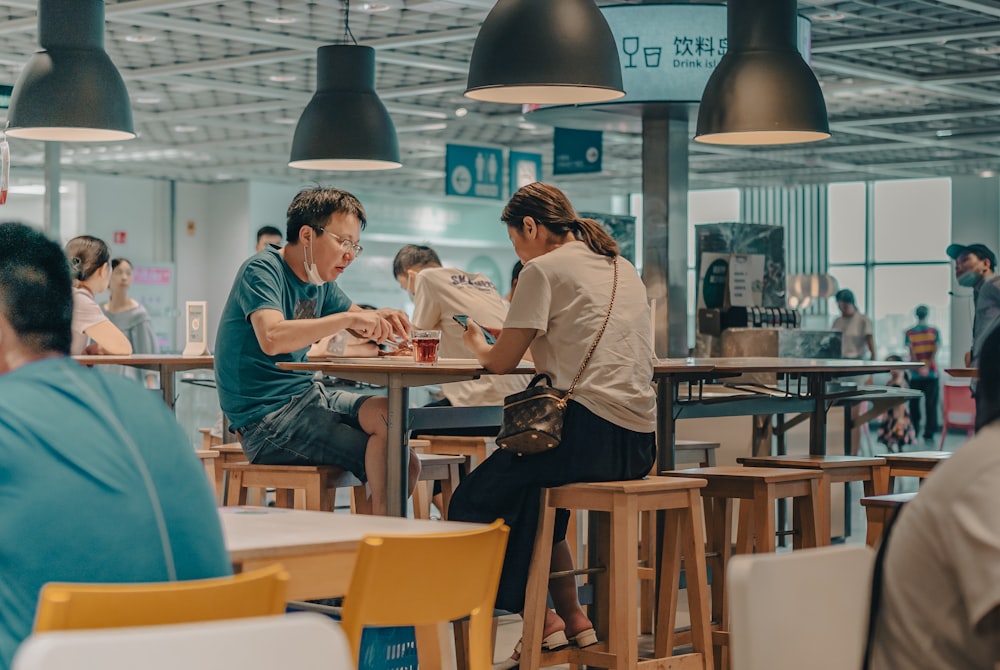 man and woman sitting on brown wooden chair in restaurant