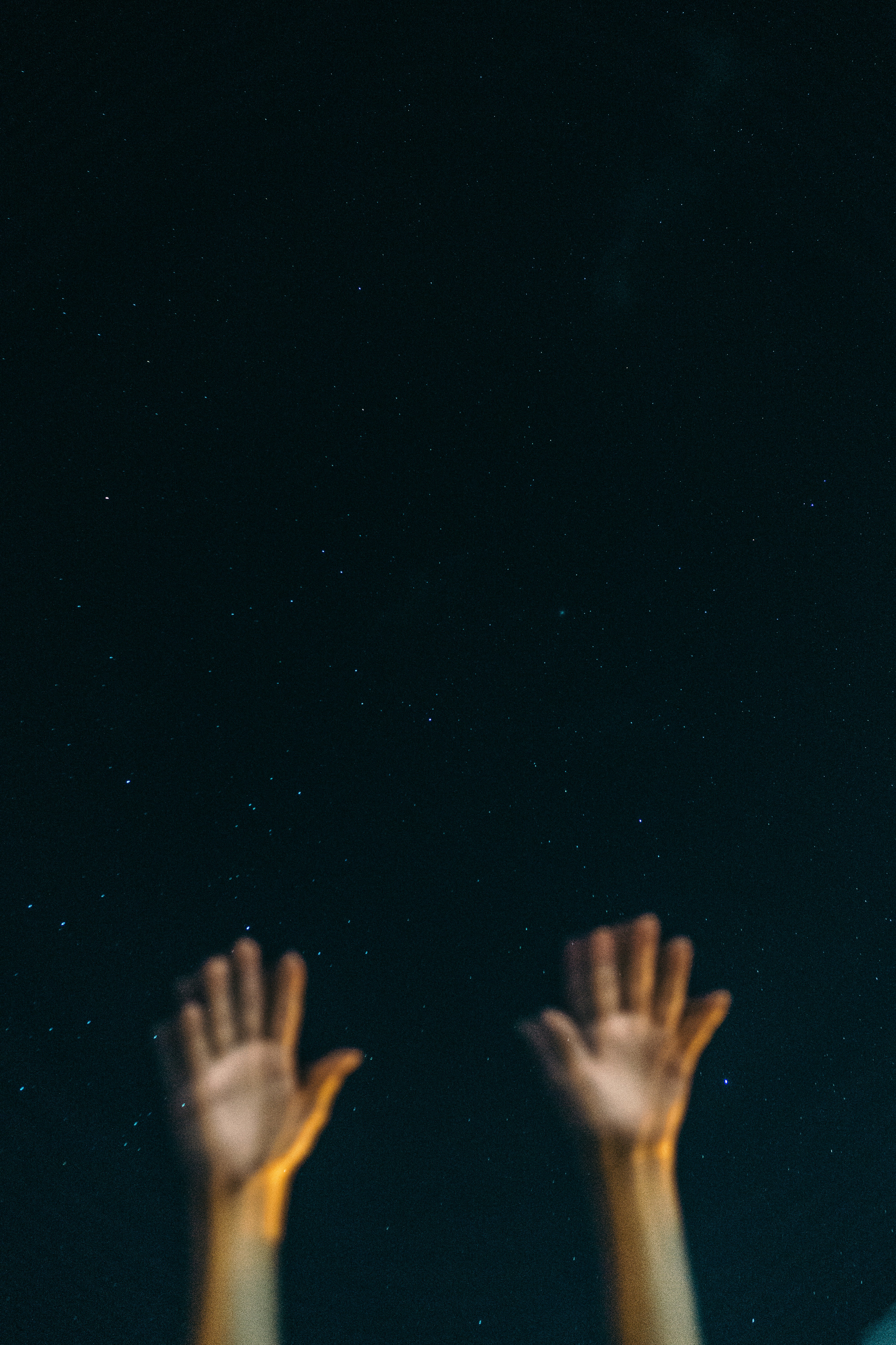 two hands reaching up into the sky at night