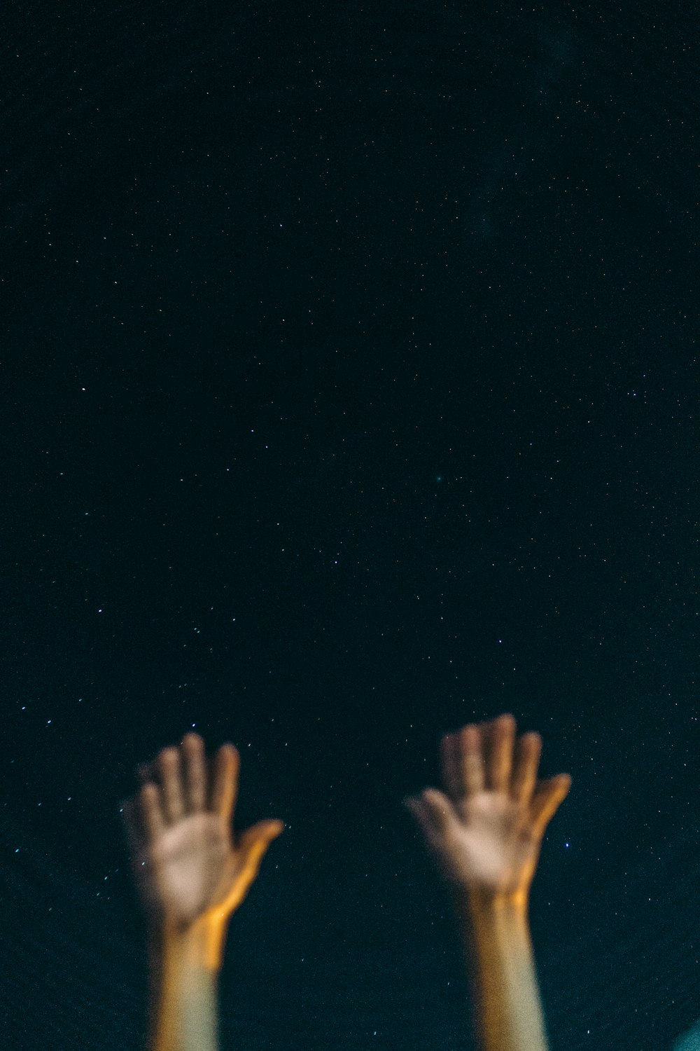 two hands reaching up into the sky at night