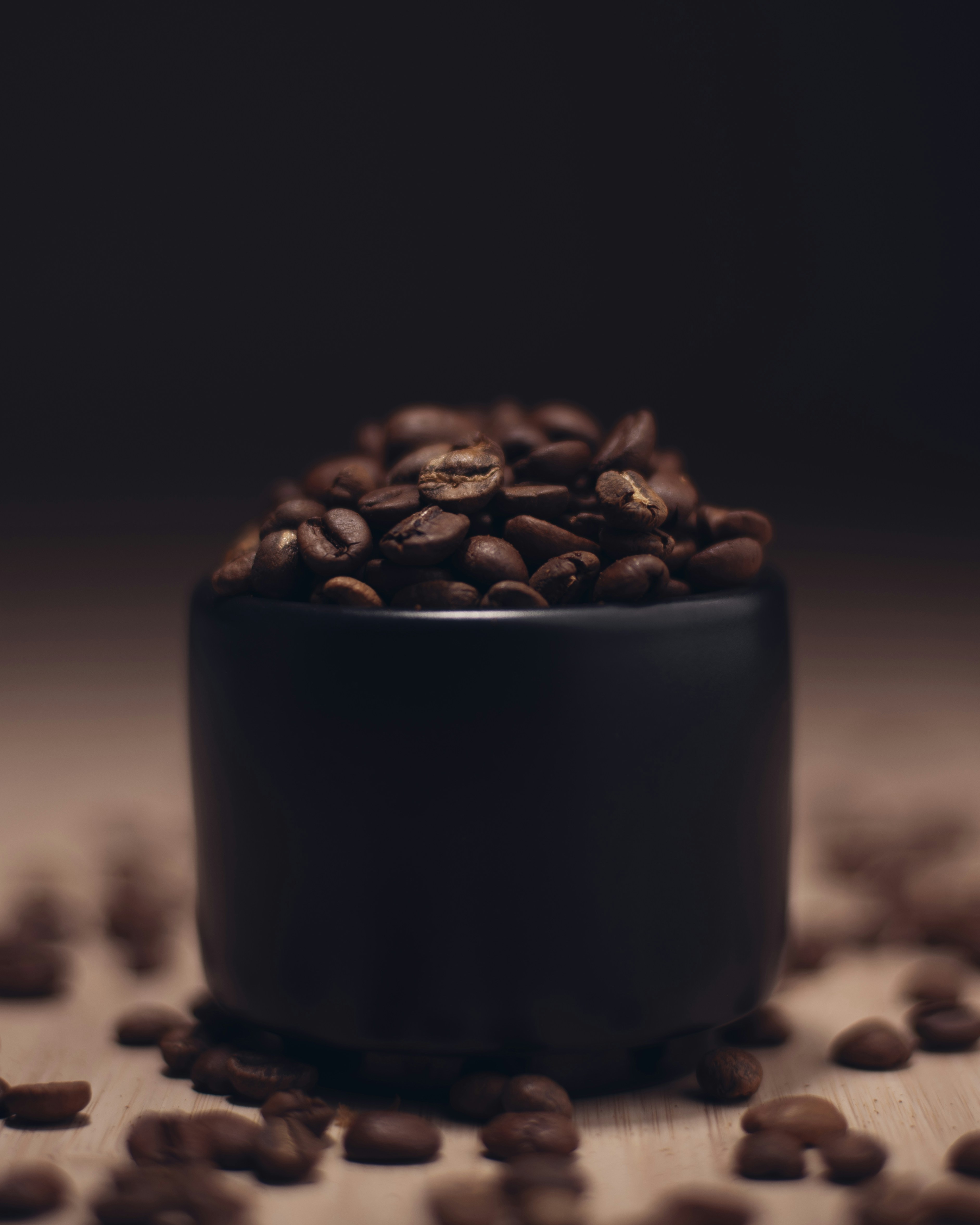 Granos de café marrones en taza de cerámica negra