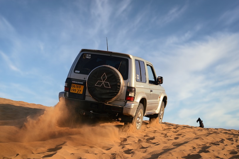 white suv on brown sand under blue sky during daytime