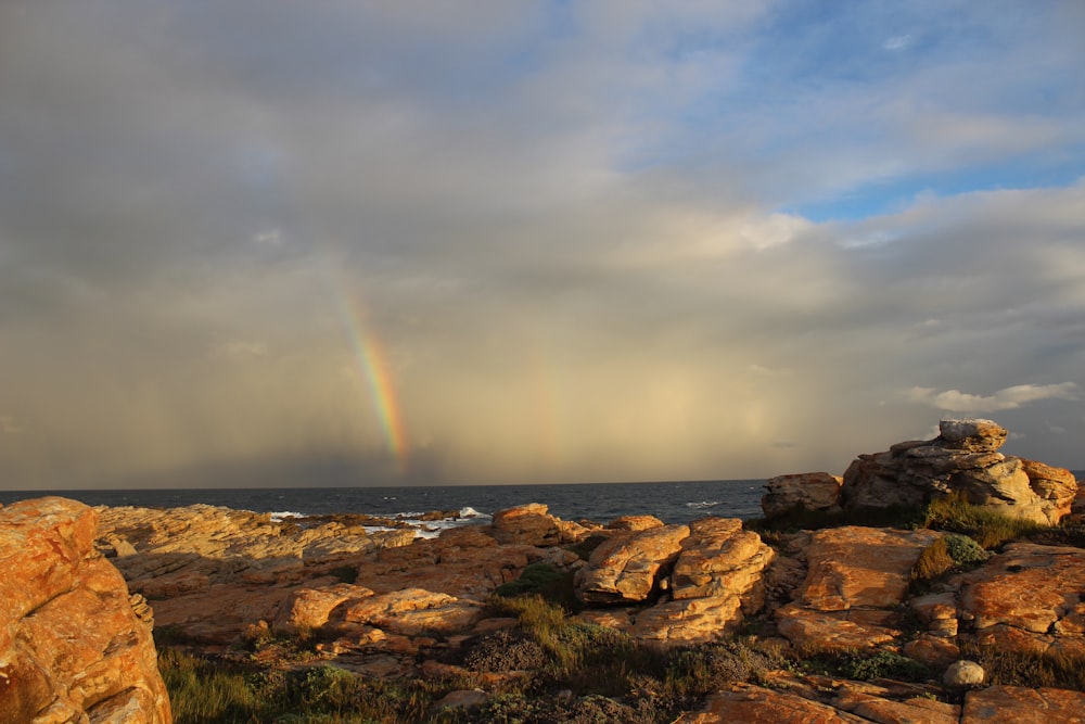 a rainbow shines in the sky over the ocean