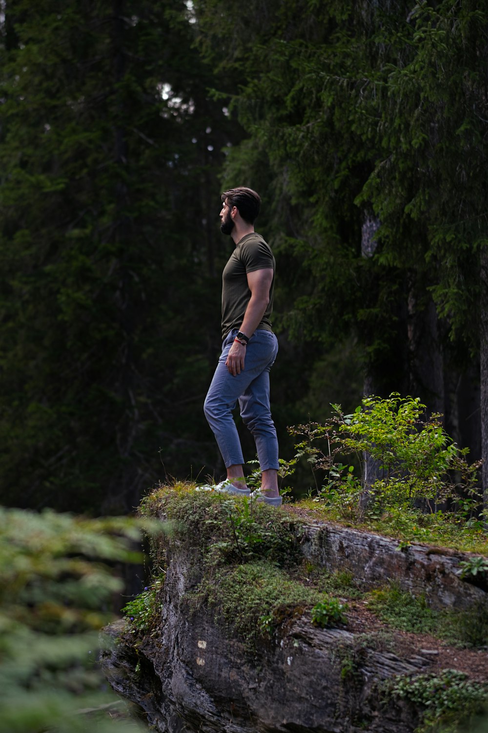 woman in gray tank top and blue denim jeans standing on gray rock during daytime