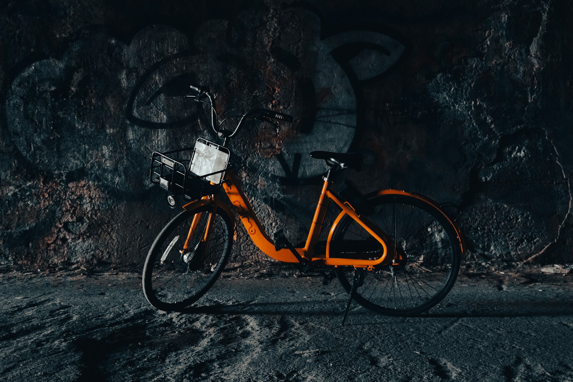 an orange bicycle parked in front of a rock wall