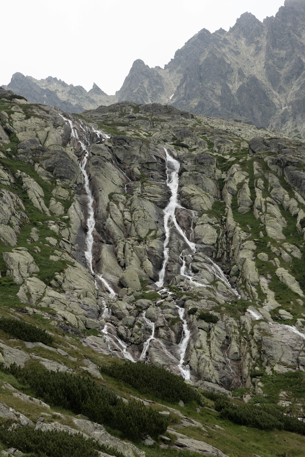 a mountain side with a stream of water running down it