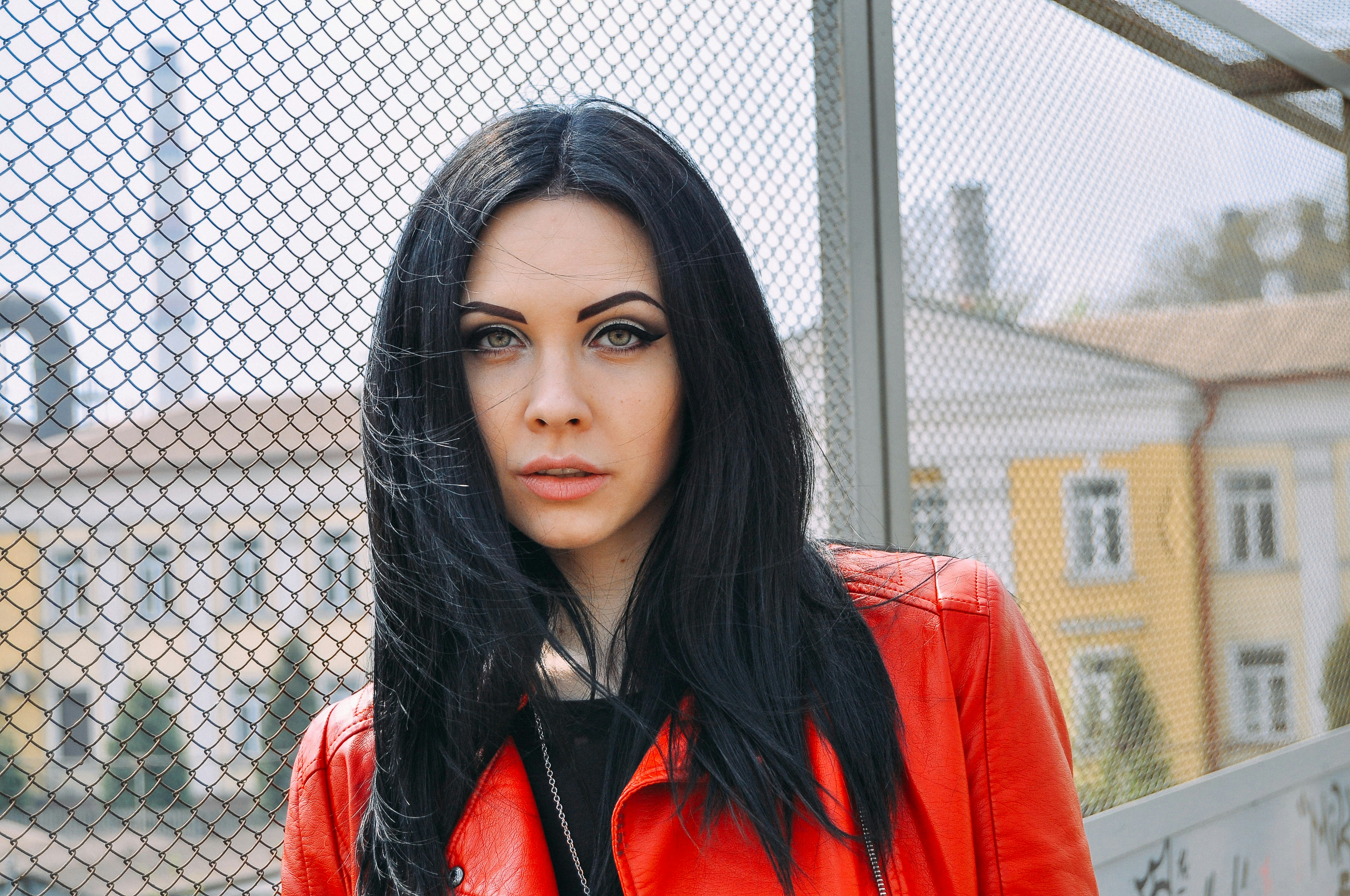 a woman with long black hair wearing a red jacket