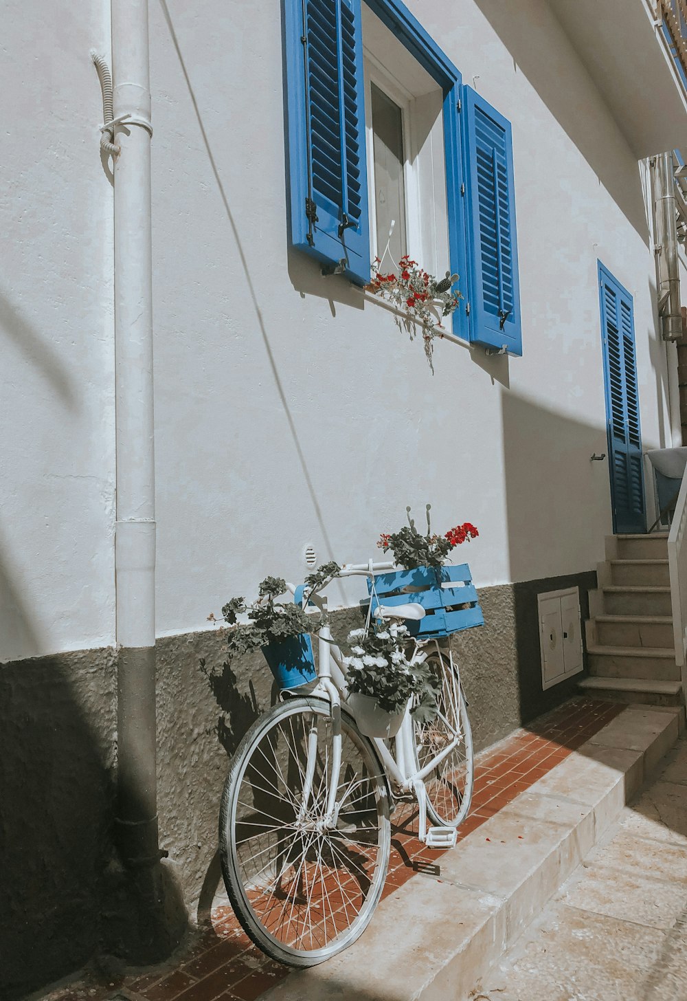 昼間、白いコンクリートの建物の脇に停車する青いシティバイク